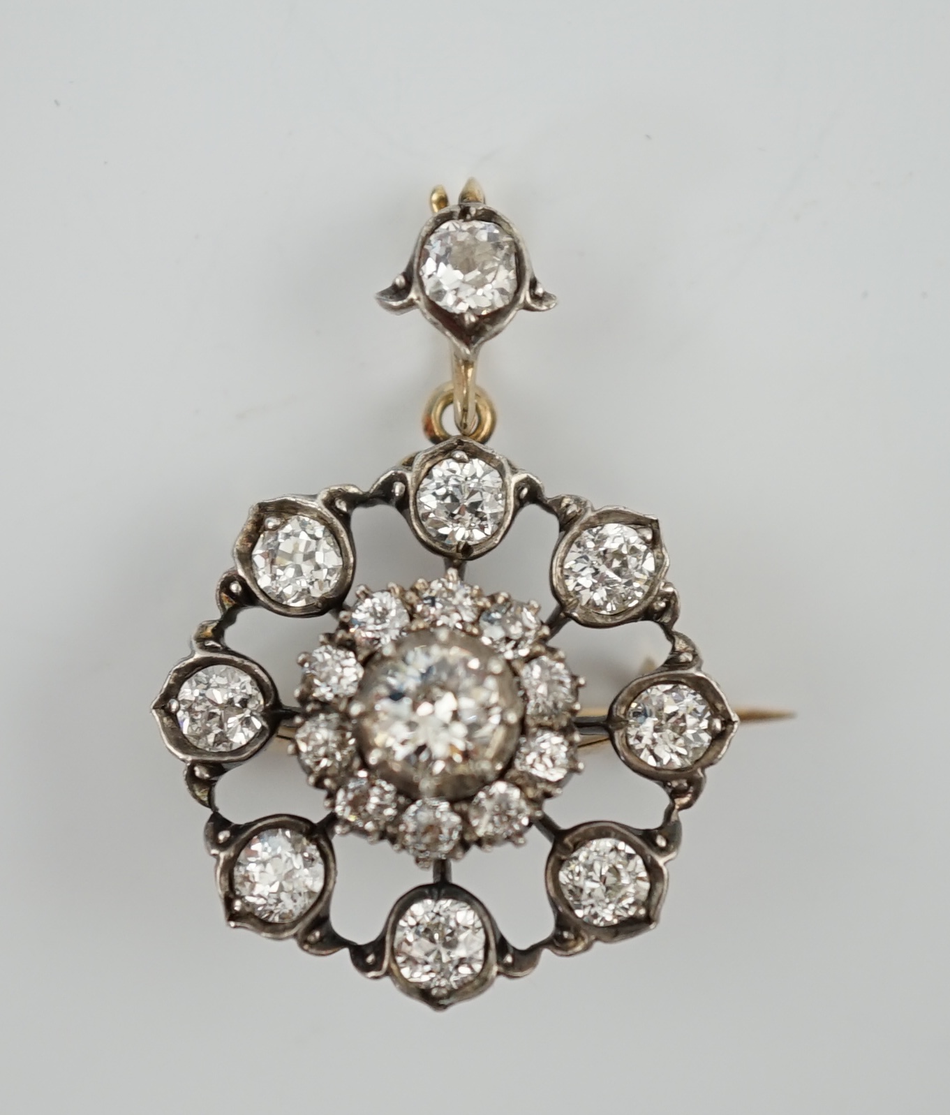 An early 20th century gold and silver mounted diamond cluster set circular pendant brooch